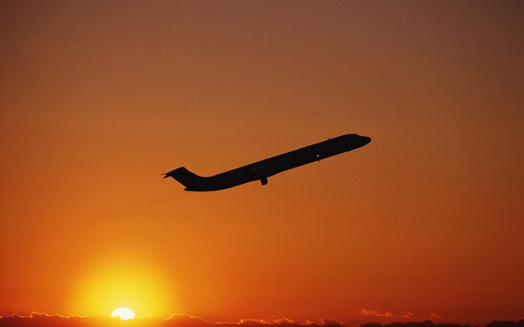 an airplane taking off while sunsets